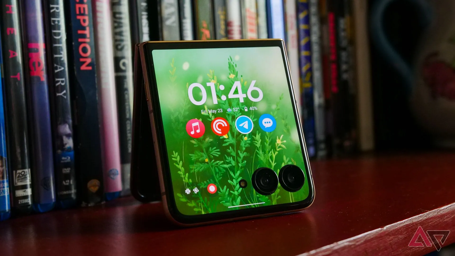 Điện thoại gập Motorola Razr Ultra (2025) với màn hình phụ hiển thị thông tin, đặt trên kệ sách.