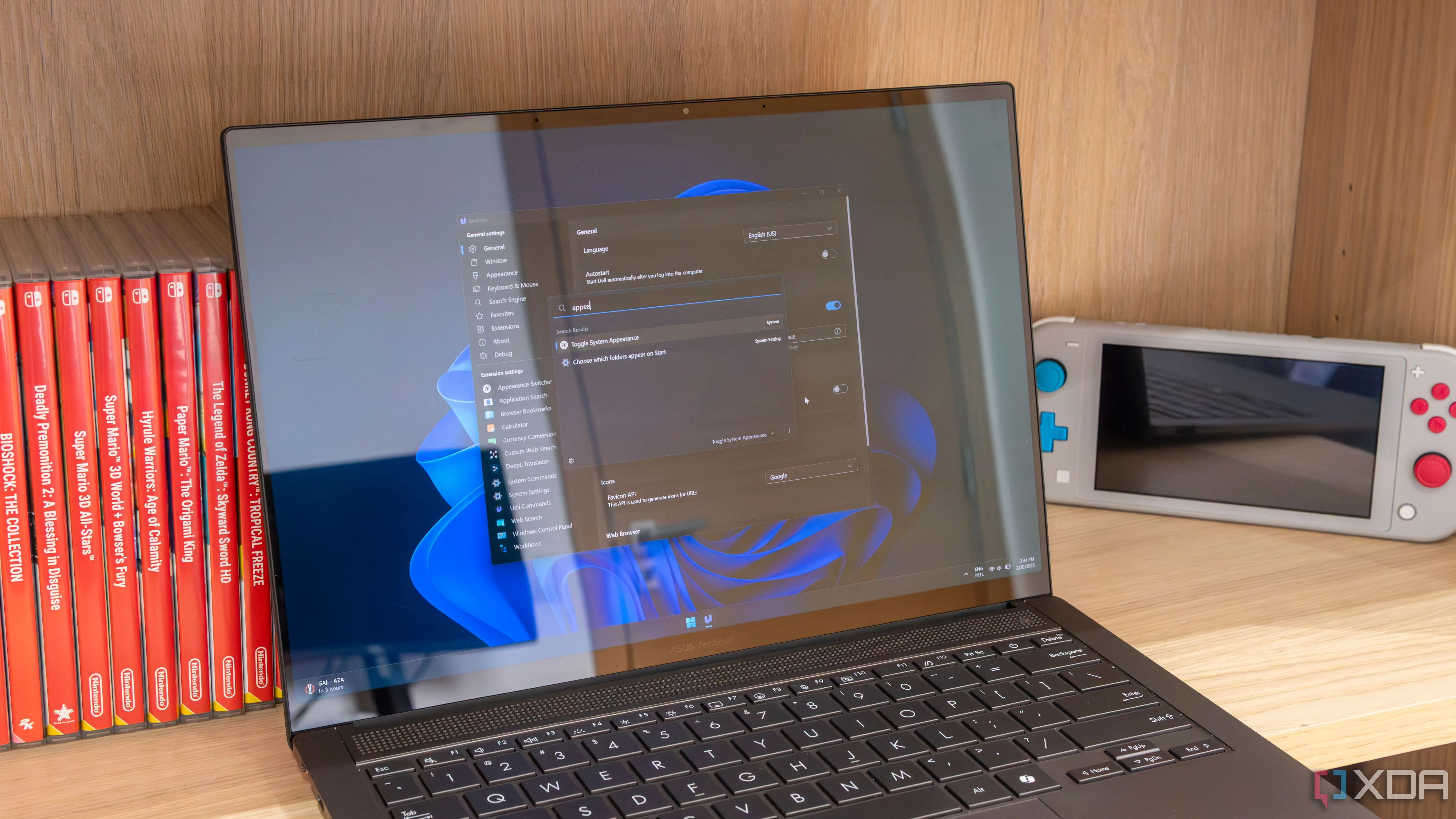 Laptop Windows 11 hiển thị cửa sổ cài đặt và thanh tìm kiếm của Ueli, một trình khởi chạy ứng dụng thông minh