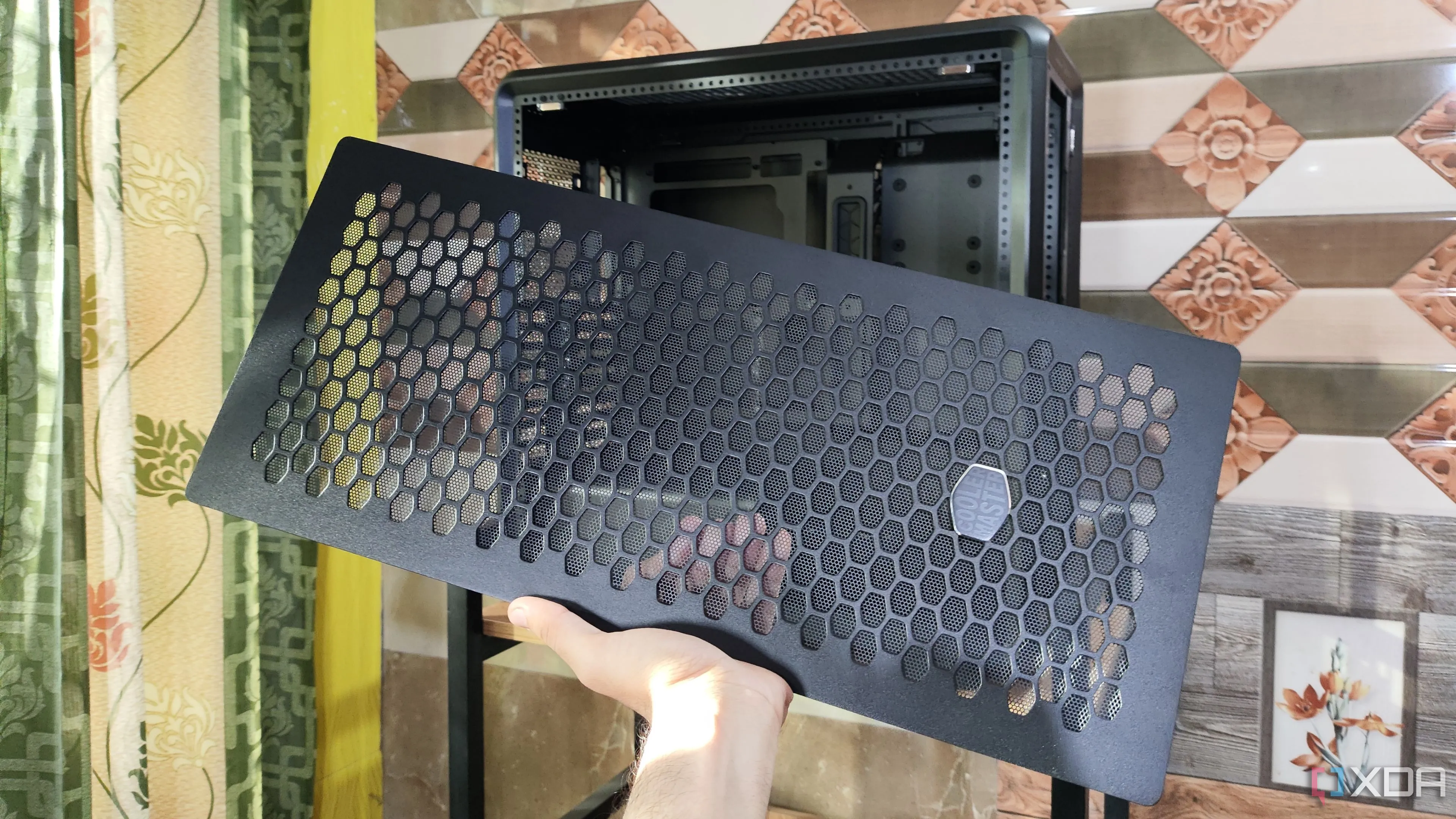 Người dùng cầm tấm mặt trước của vỏ case Cooler Master MasterFrame 600, thể hiện tính linh hoạt nhưng chưa hoàn toàn modular
