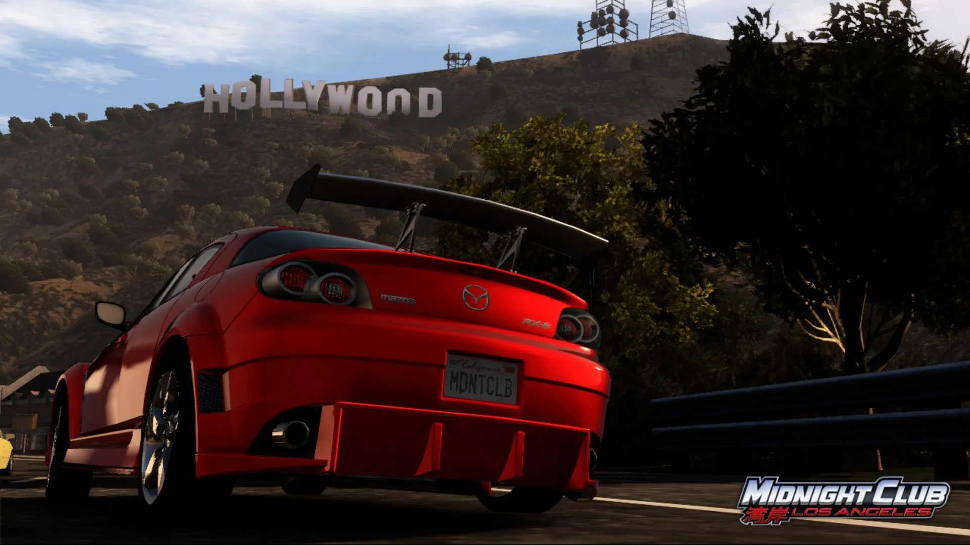 Ảnh chụp màn hình từ Midnight Club: Los Angeles, một chiếc Mazda màu cam đang chạy trên đường phố với biển hiệu Hollywood phía sau