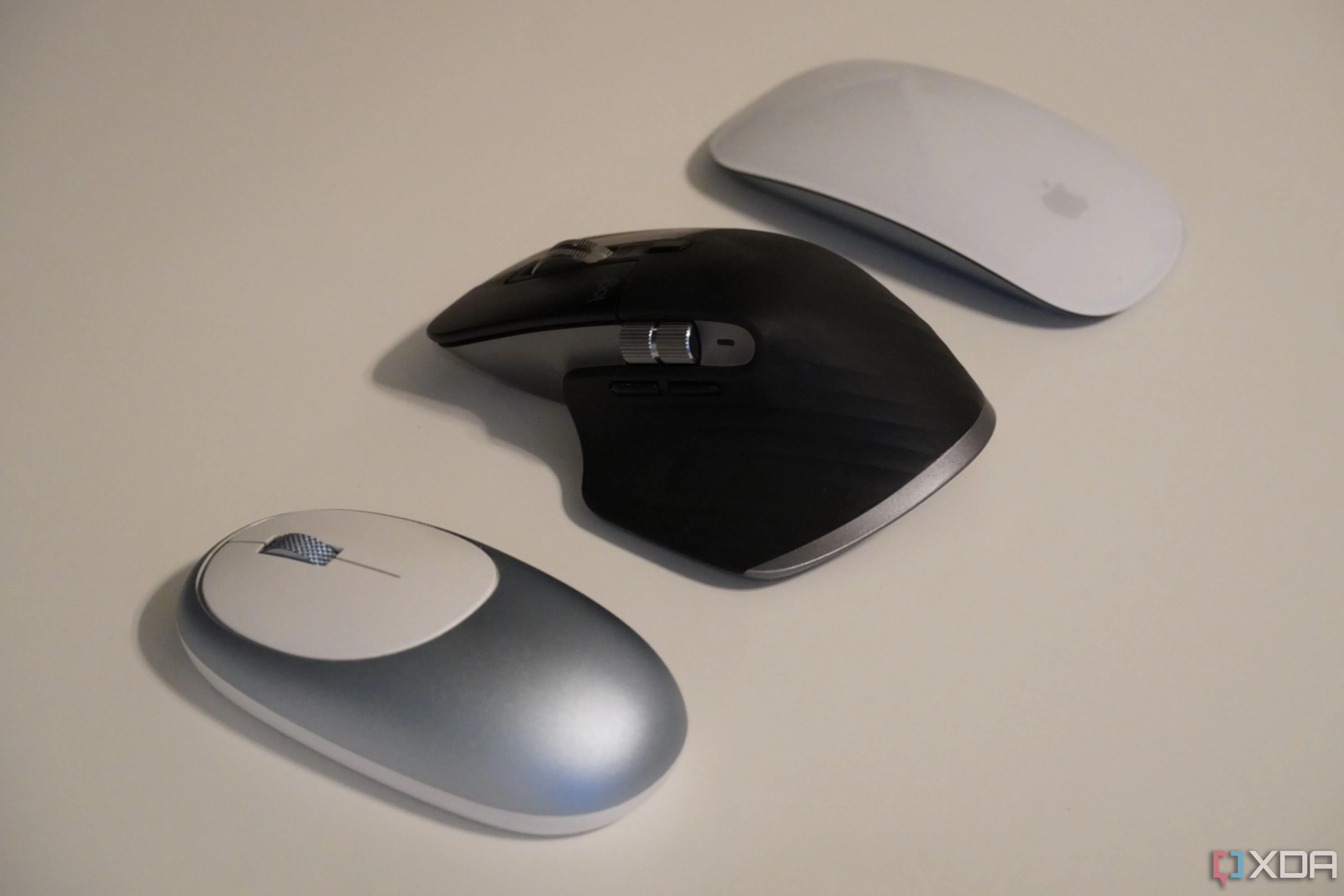 Ba con chuột máy tính, trong đó có Logitech MX Master 3, trên bàn làm việc, thể hiện sự so sánh tổng thể về thiết kế.