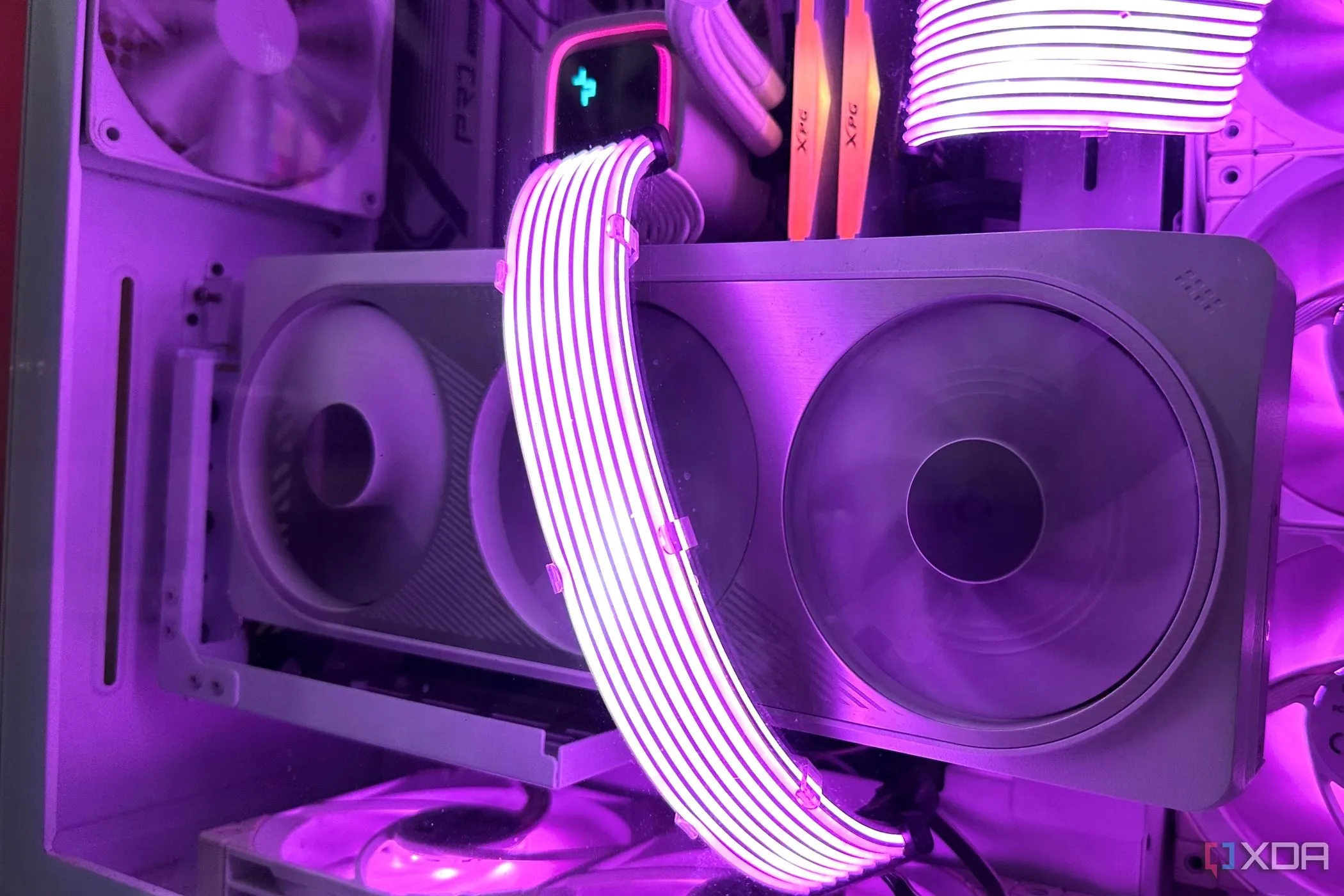 Card đồ họa Nvidia RTX 4070 Ti màu trắng trong vỏ máy tính tông trắng với dây cáp Lian Li Strimer phát sáng màu tím.