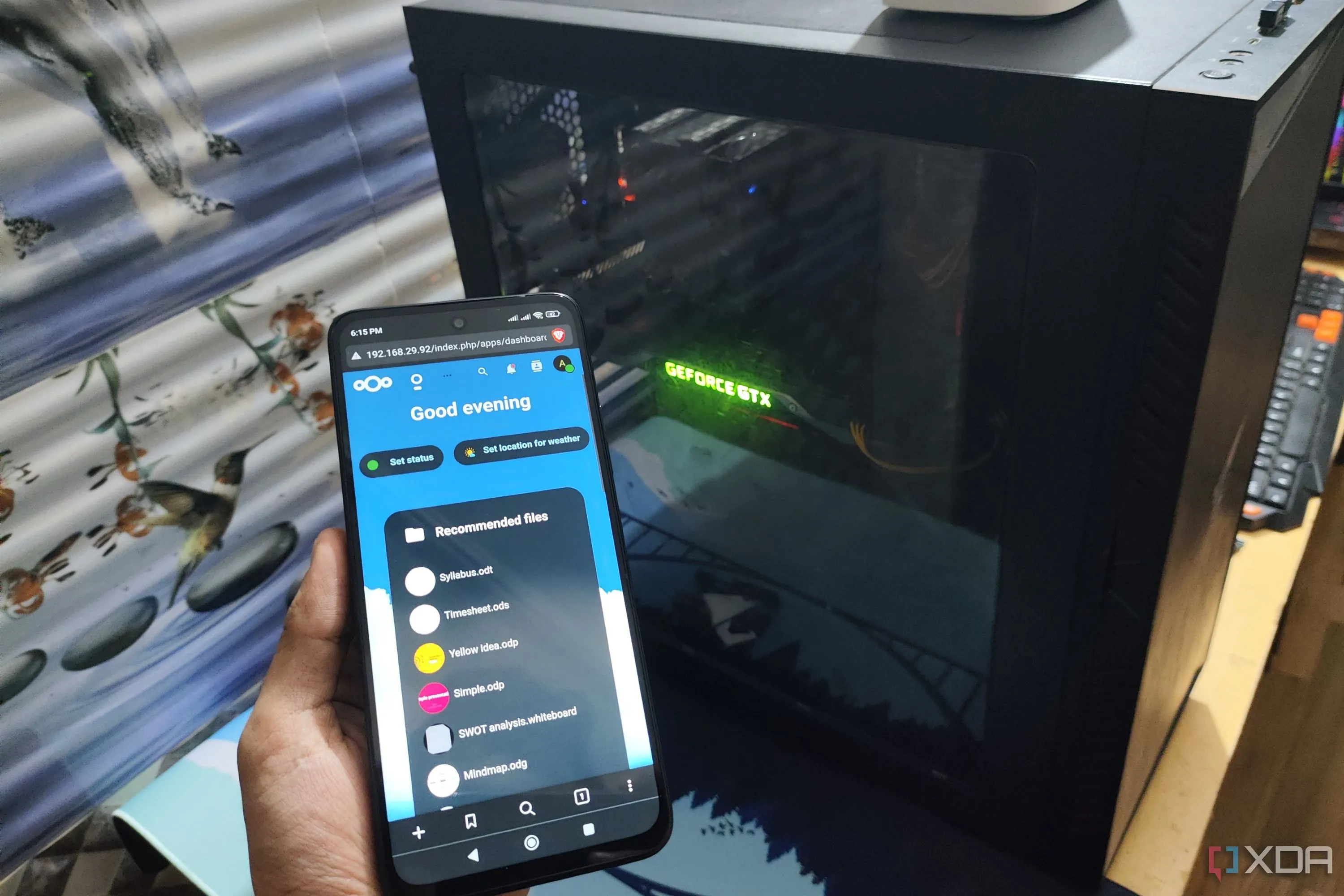 Giao diện người dùng Nextcloud hiển thị trên điện thoại Poco M6 Pro, với máy tính để bàn ở phía sau