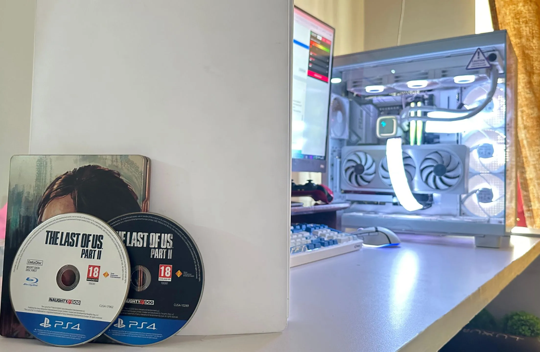 Hai đĩa game The Last of Us Part II phiên bản PS4 đặt cạnh PC và PS5, thể hiện dung lượng game ngày càng lớn.