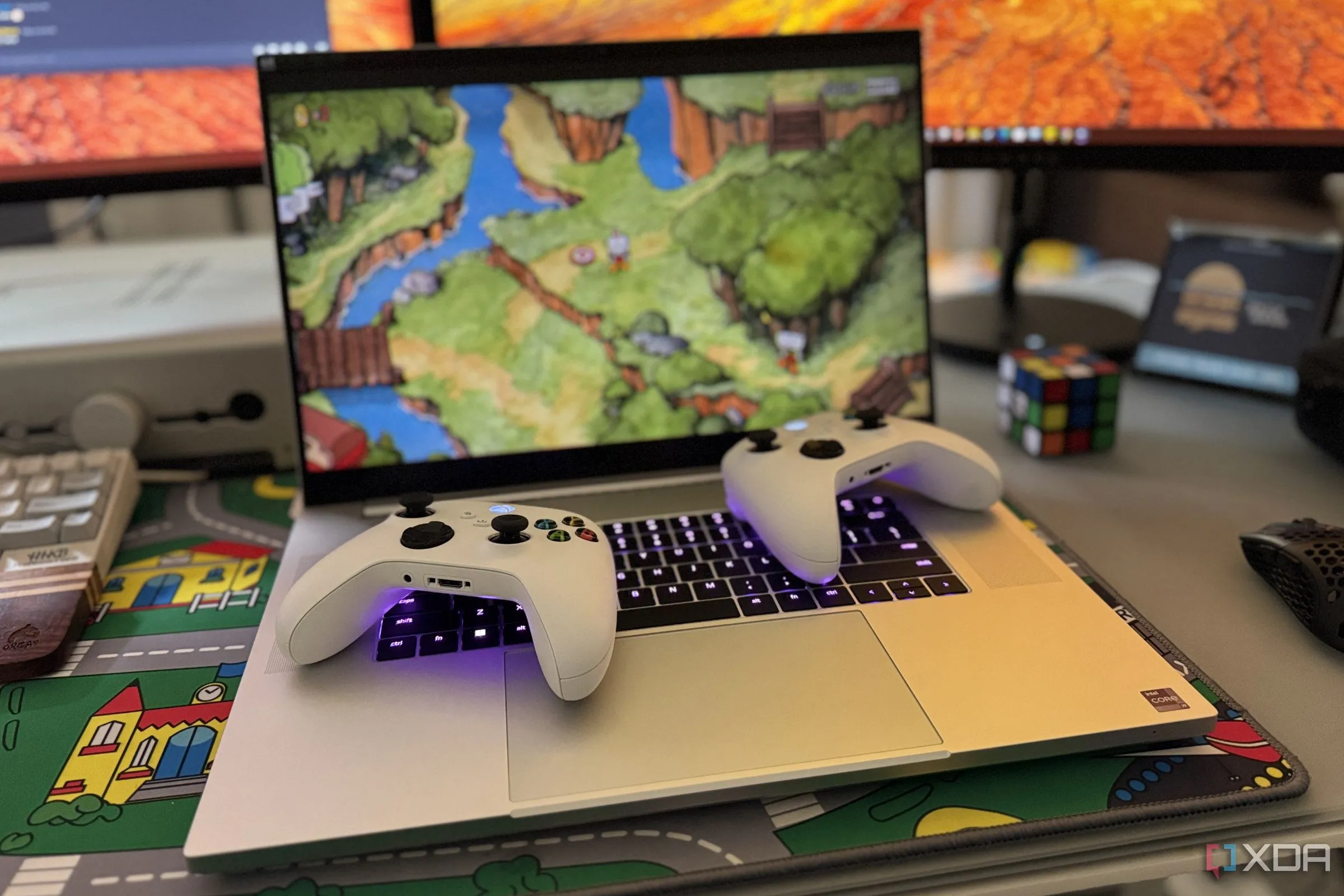 Hai tay cầm Xbox không dây đặt trên laptop Razer Blade 18 đang hiển thị game Cuphead, minh họa trải nghiệm gaming.
