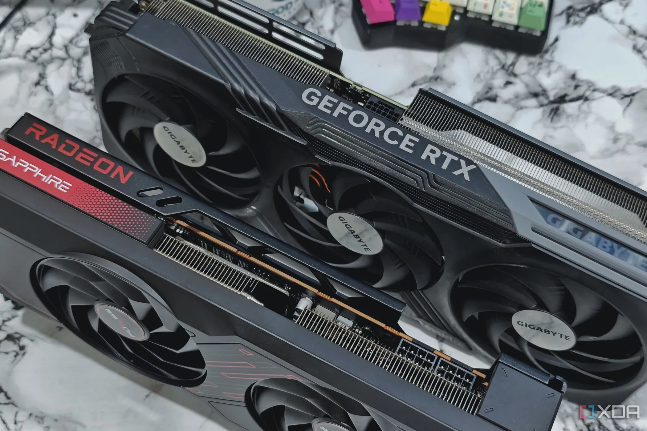 Hình ảnh hai card đồ họa Nvidia GeForce RTX 4070 Ti và AMD Radeon RX 7700 XT trên bàn làm việc