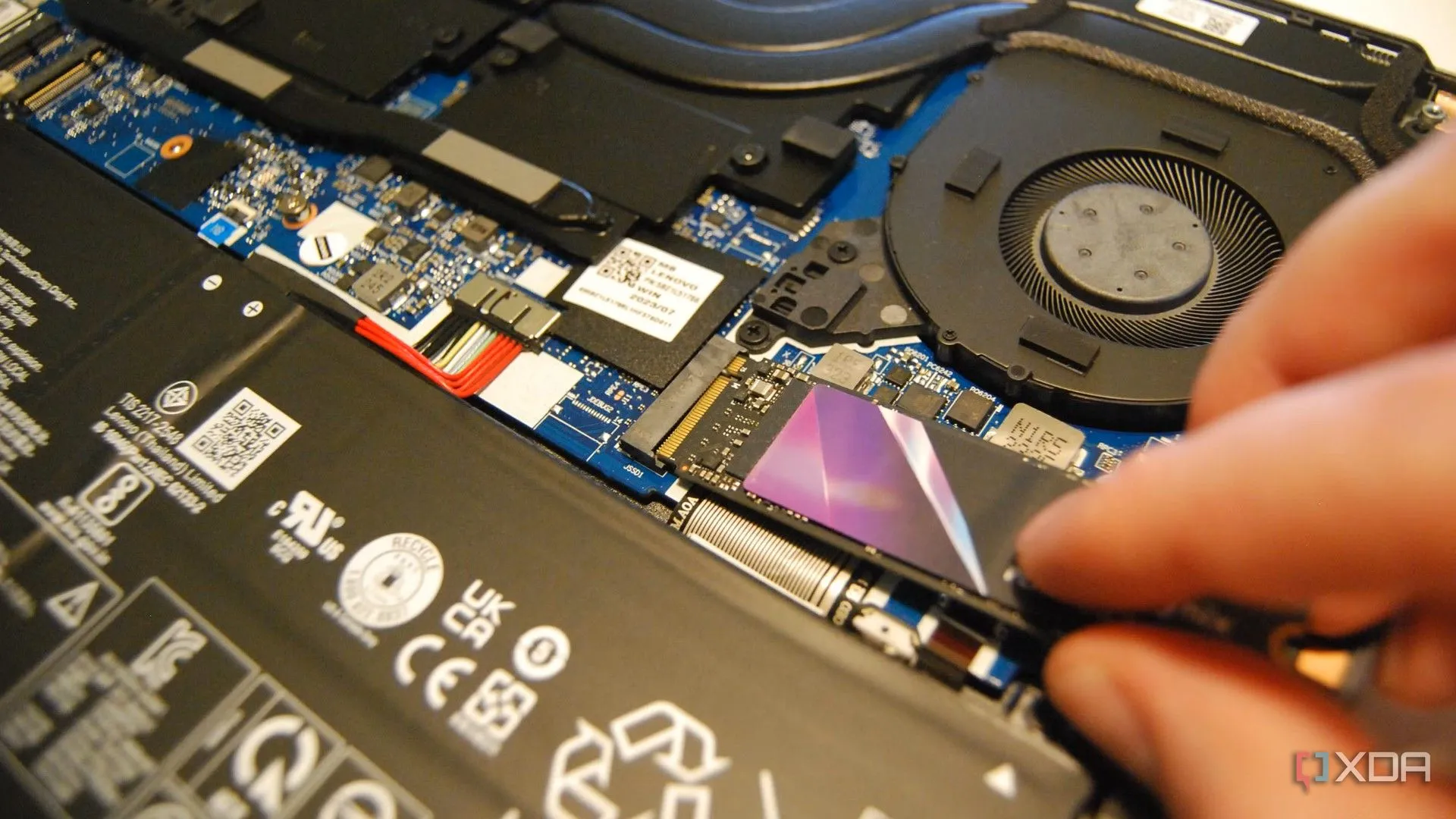 Hình ảnh người dùng đang lắp ổ cứng M.2 SSD vào laptop để giải quyết vấn đề dung lượng lưu trữ cho hệ thống dual-boot