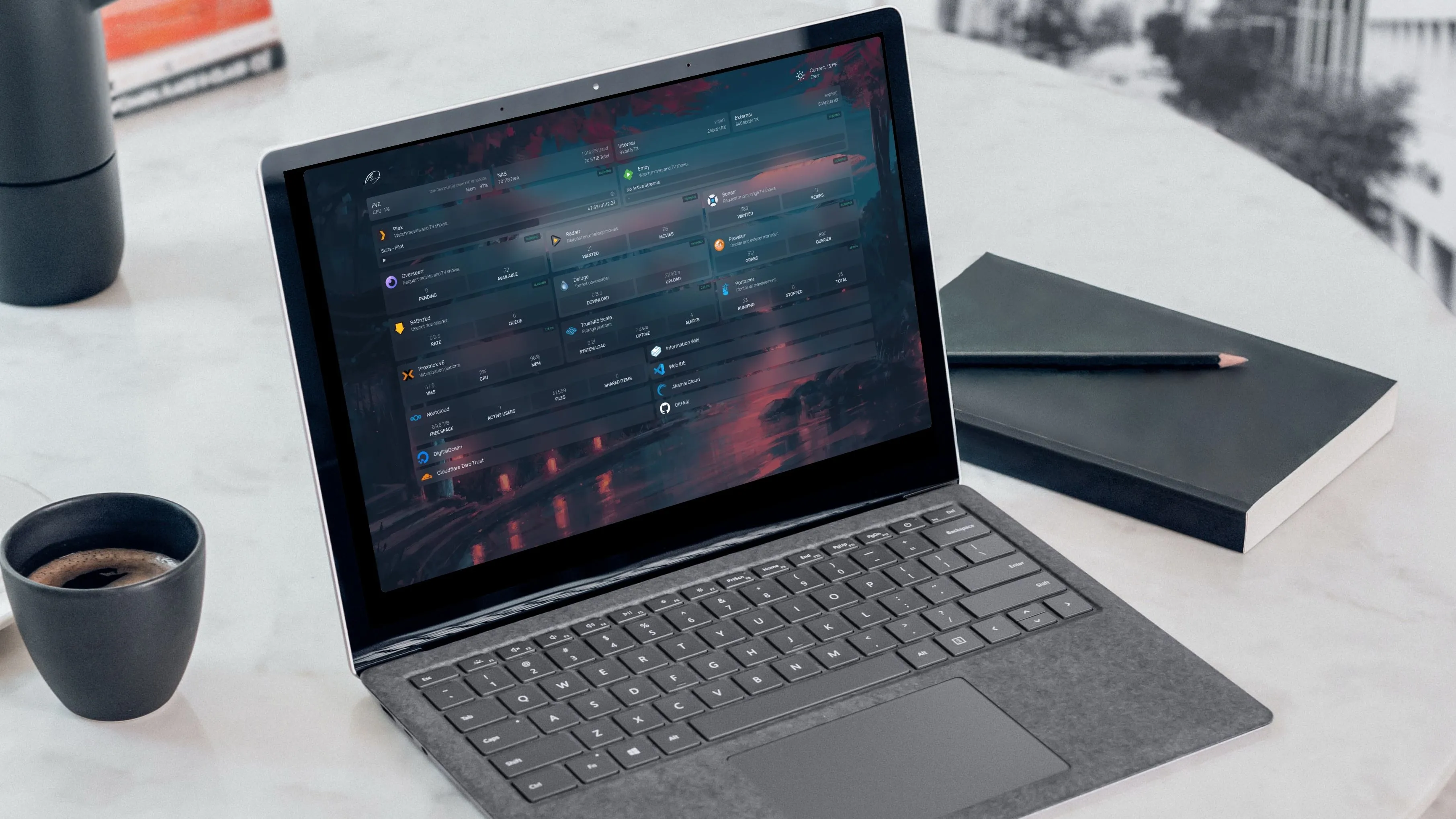Laptop hiển thị dashboard các ứng dụng tự host, bên cạnh ly cà phê và sổ ghi chép