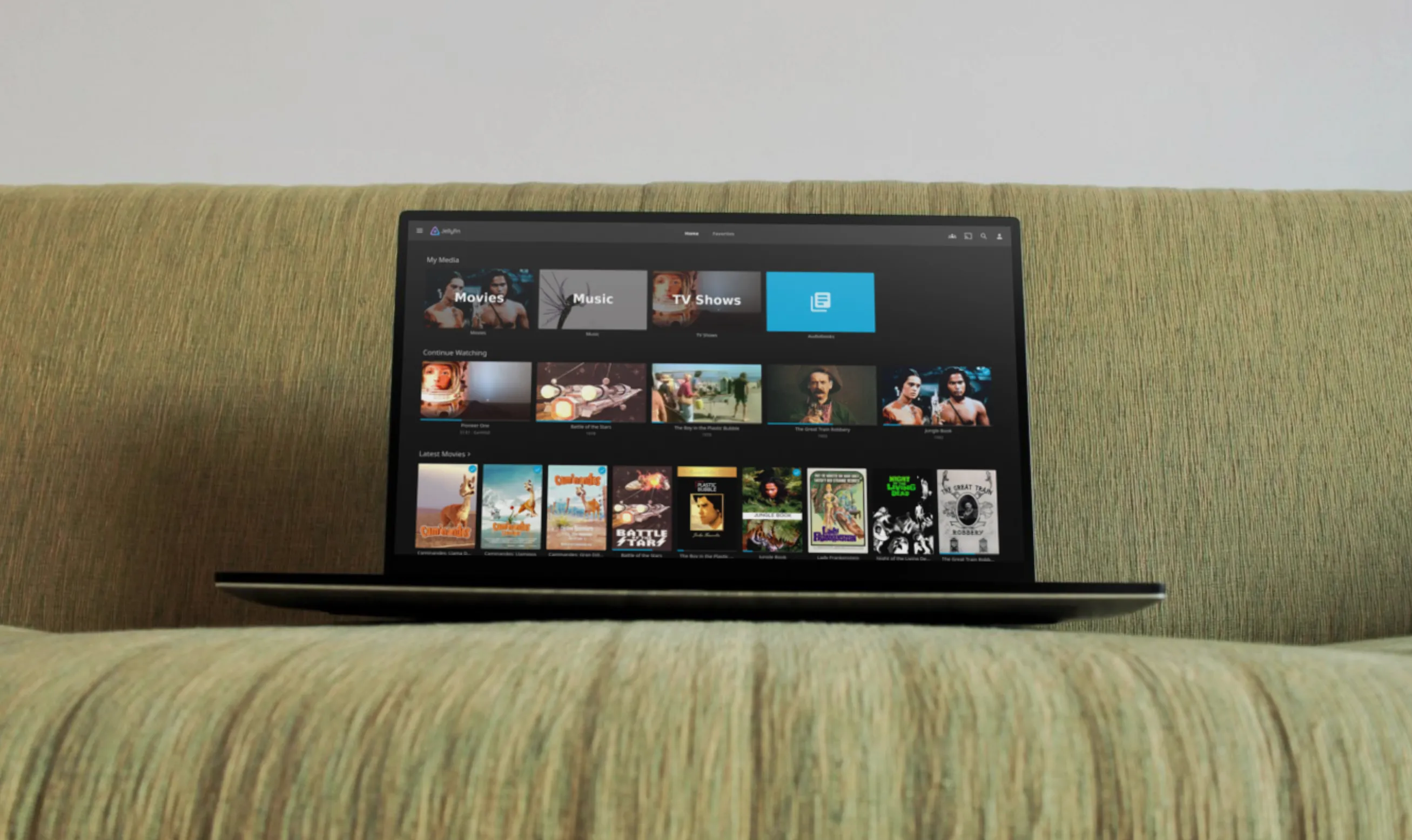 Laptop và điện thoại hiển thị Jellyfin trên bàn sofa