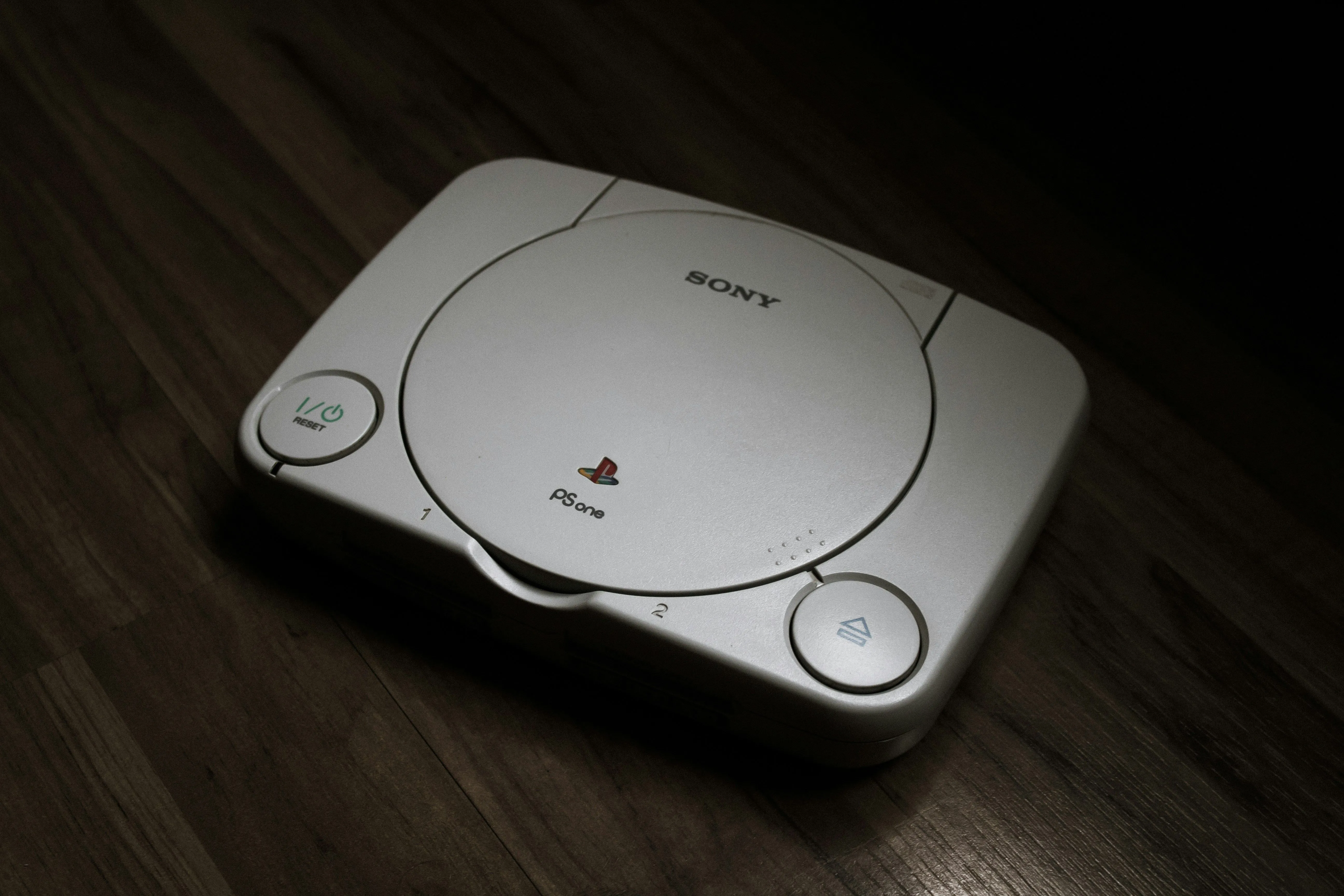 Máy chơi game PlayStation 1 đặt trên sàn gỗ, thể hiện sự giao thoa phần cứng với PC