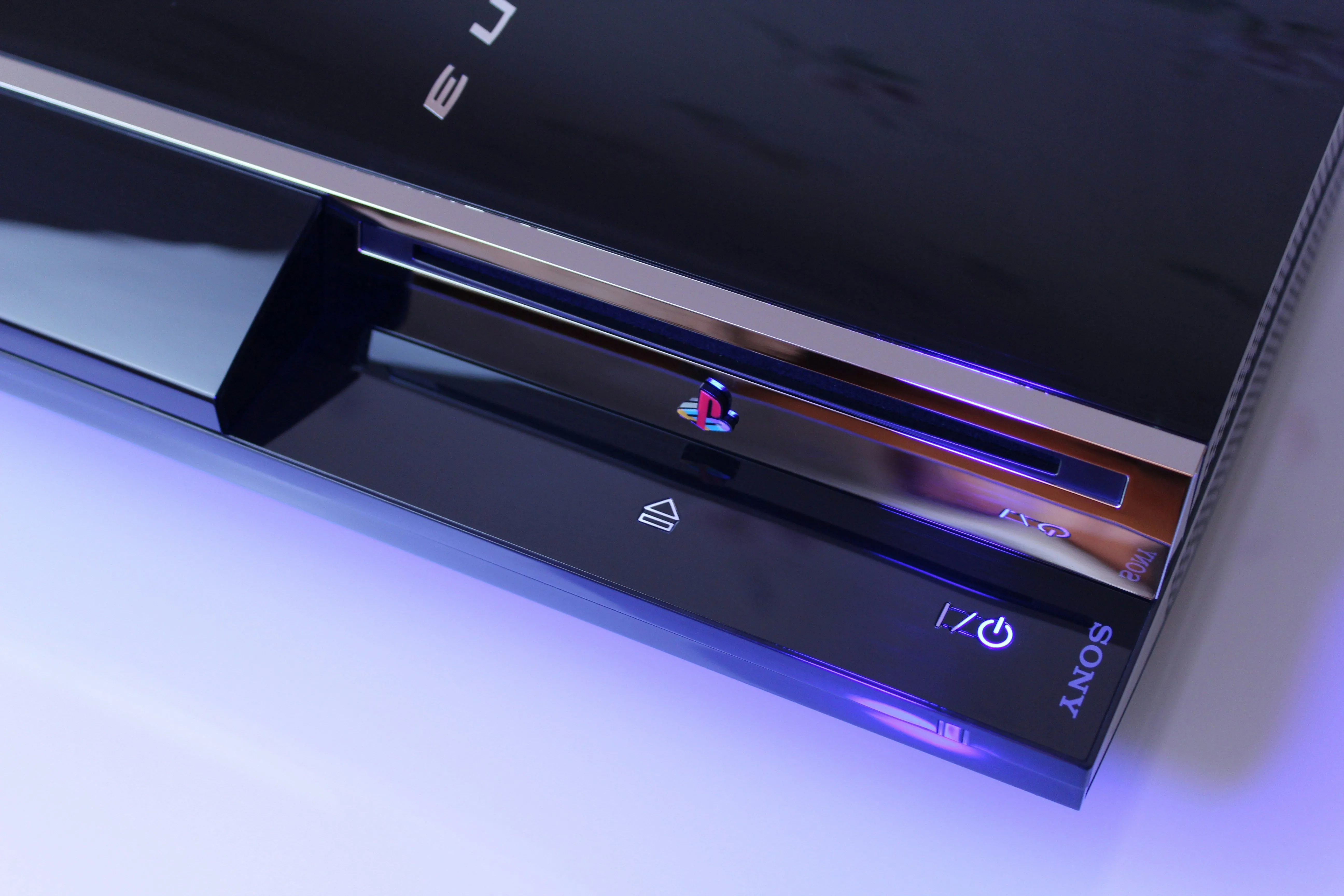 Máy chơi game PlayStation 3 màu đen nhìn từ góc bên, hiển thị khay đĩa và nút nguồn