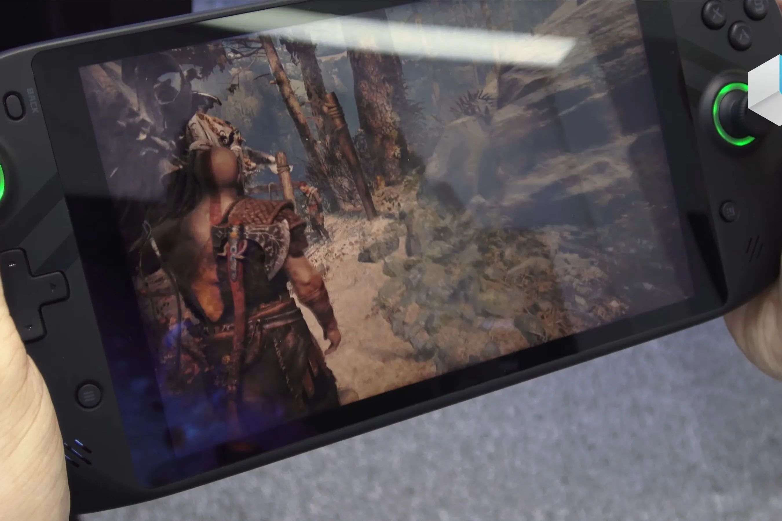 Một chiếc máy chơi game cầm tay đang chạy God of War, thể hiện đồ họa sống động trên màn hình nhỏ
