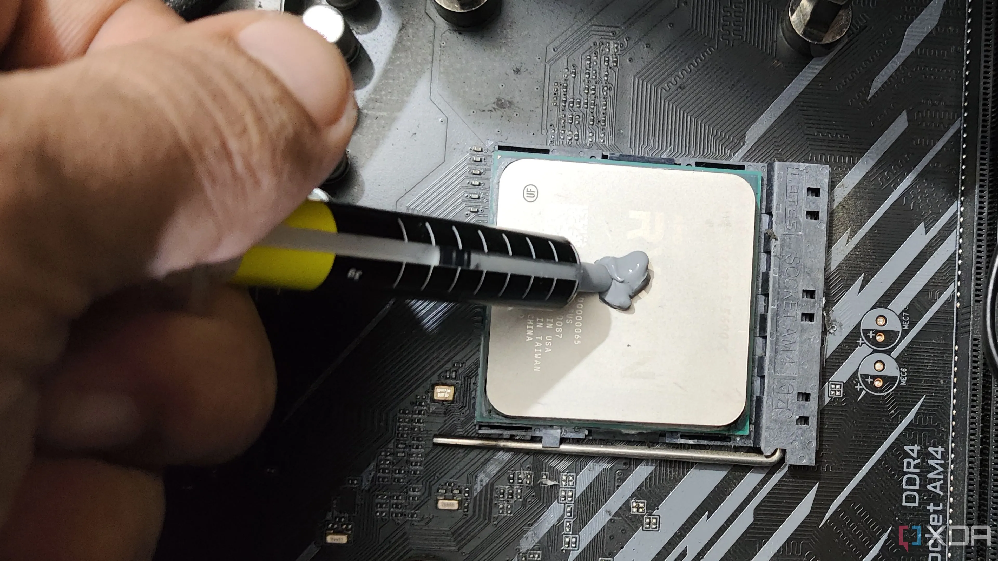 Một người đang bôi keo tản nhiệt lên bộ vi xử lý AMD Ryzen 5 5600X