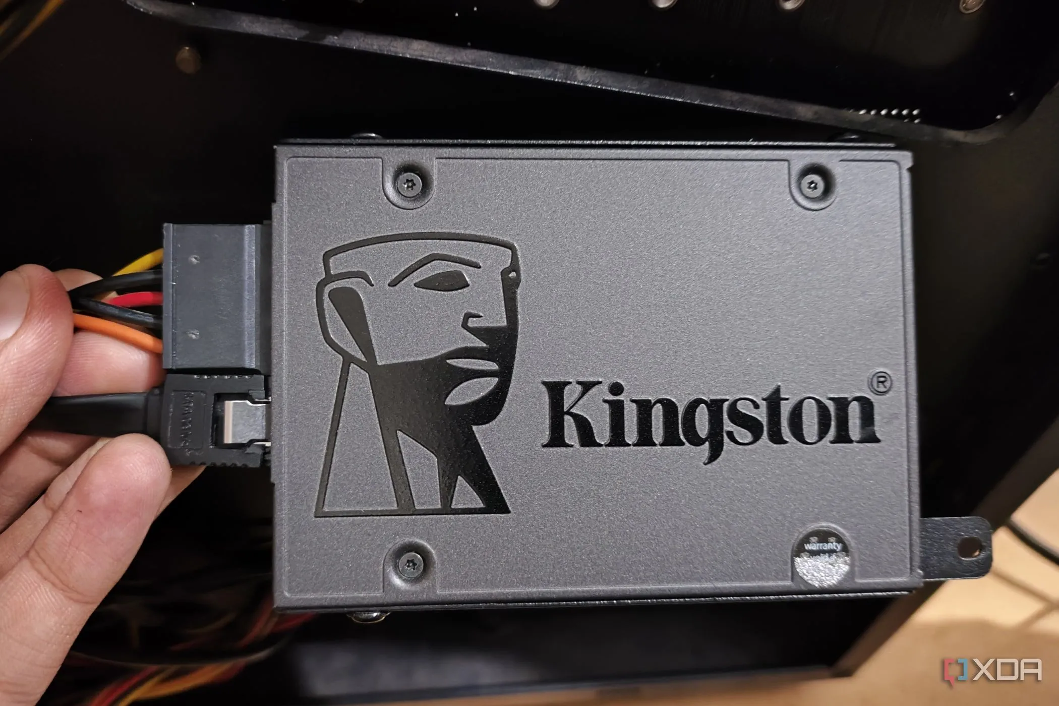 Một người đang cầm ổ cứng SSD đã cắm cáp SATA dữ liệu và nguồn