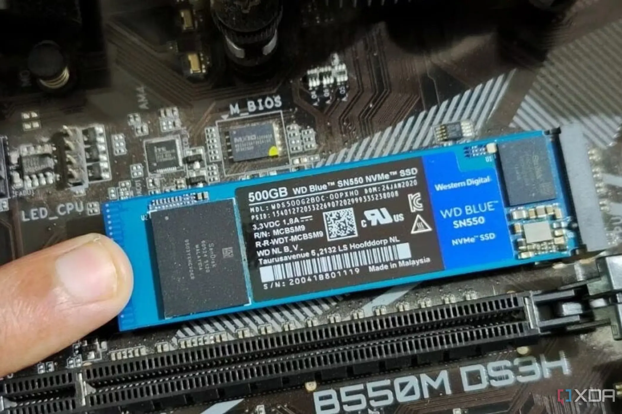 Một người đang giữ mô-đun SSD M.2 tại vị trí trên bo mạch chủ, minh họa quá trình lắp đặt SSD