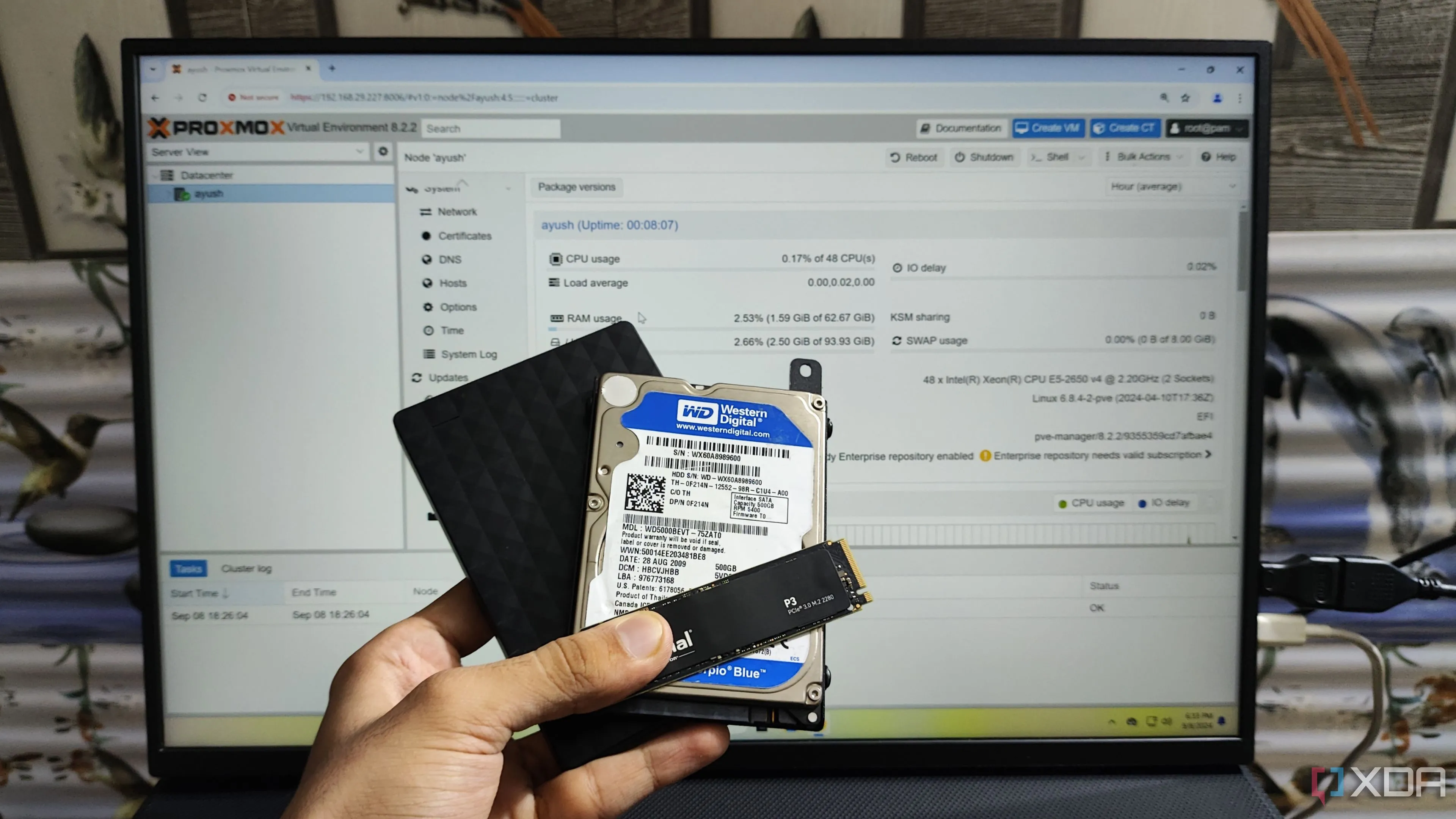 Người dùng cầm ổ SSD, HDD nội và HDD gắn ngoài trước màn hình hiển thị giao diện Proxmox, minh họa sự đa dạng của thiết bị lưu trữ.