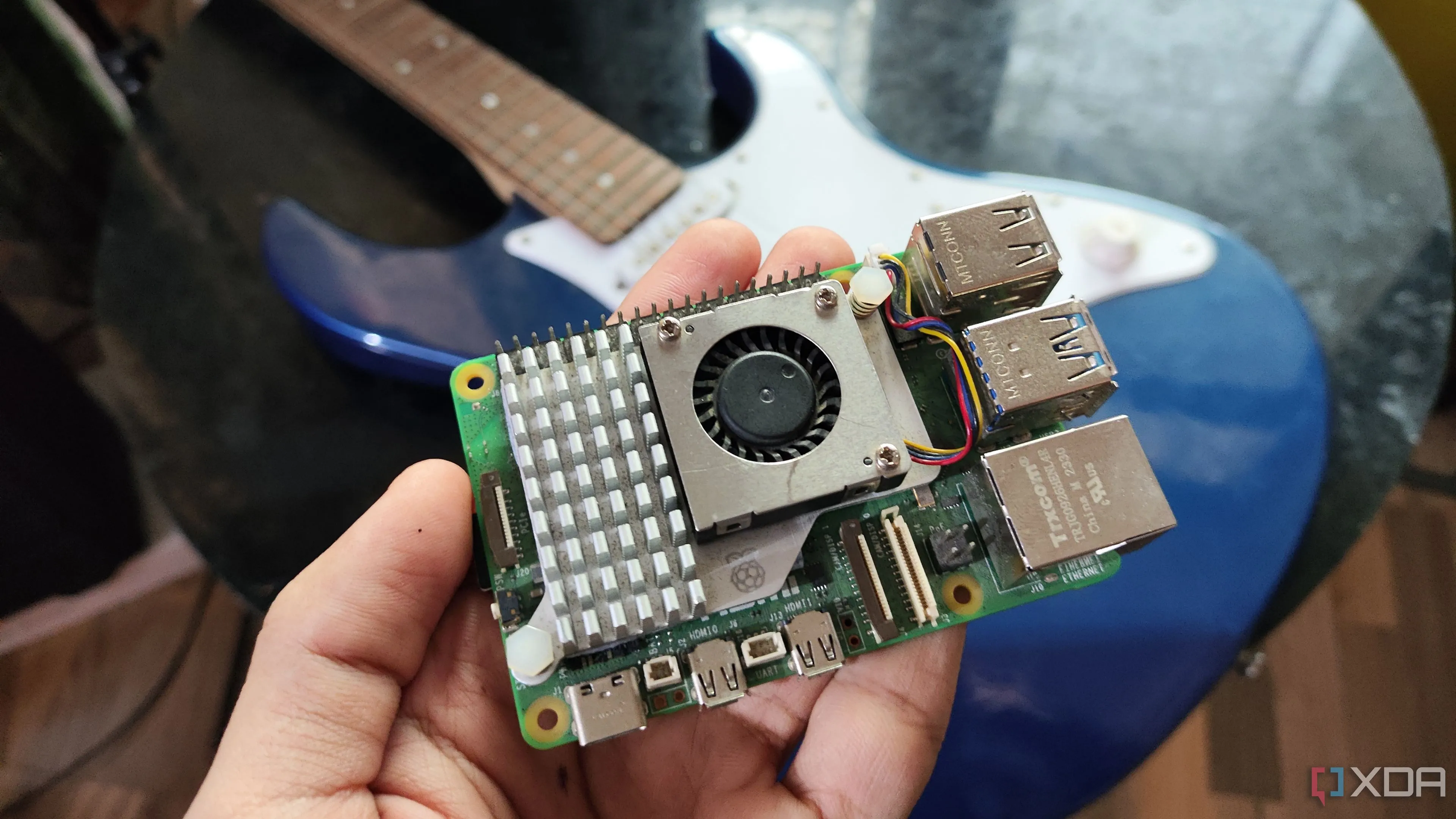 Người dùng cầm Raspberry Pi 5 trước đàn guitar, minh họa khả năng tự động hóa trên Raspberry Pi