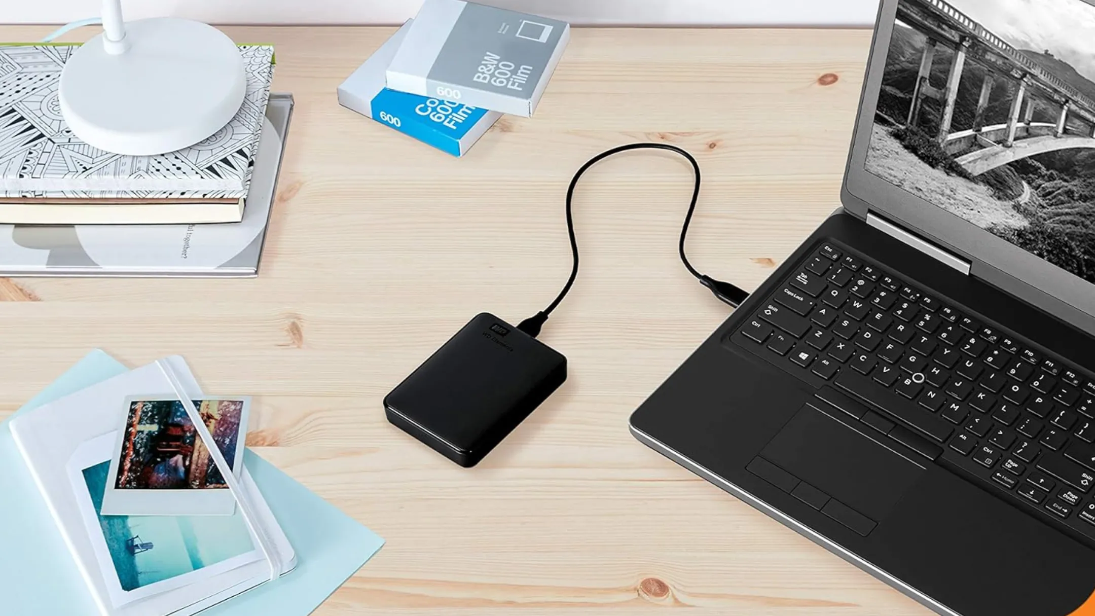 Ổ đĩa cứng gắn ngoài WD 5TB Elements Portable được kết nối với laptop trên bàn làm việc