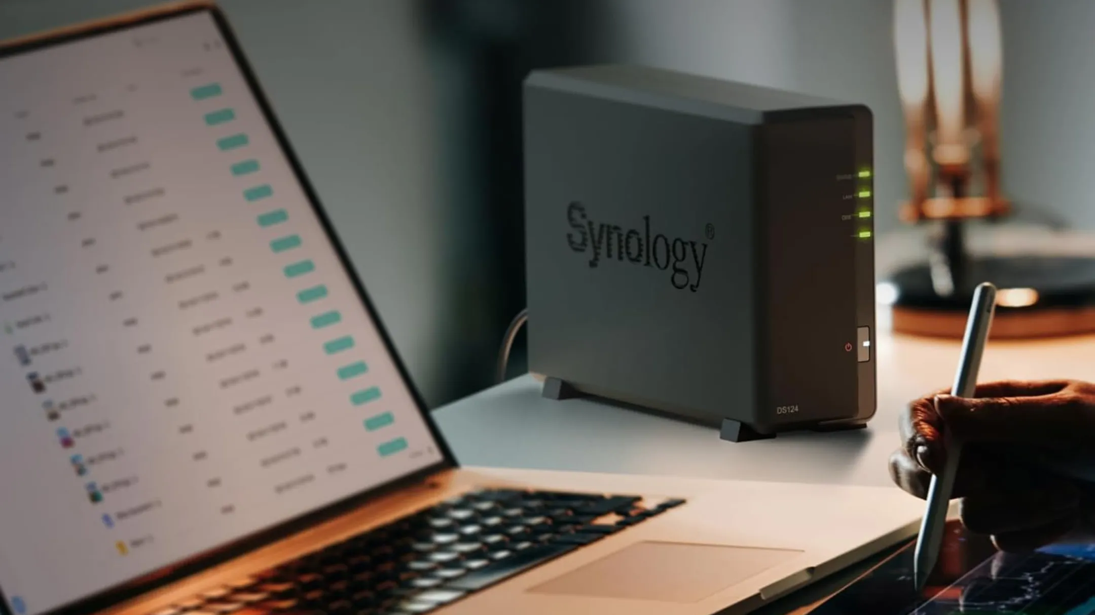 Thiết bị NAS Synology DS124 đặt gọn gàng trên bàn làm việc, bên cạnh máy tính xách tay, minh họa cho việc sử dụng tại nhà.