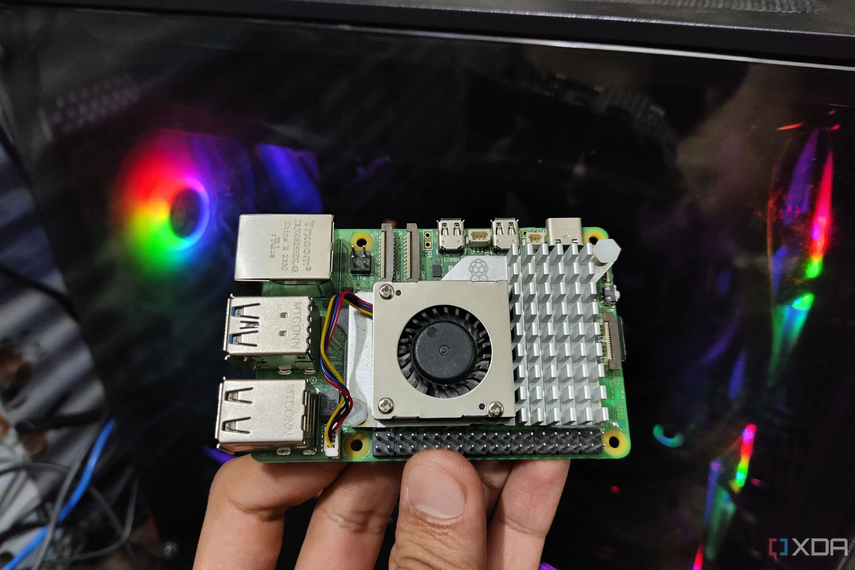 Thiết bị Raspberry Pi 5 được cầm trước máy tính, thể hiện việc lập lịch cron jobs hiệu quả